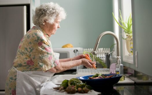 woman wearing yellow and pink floral dress wahing carrots