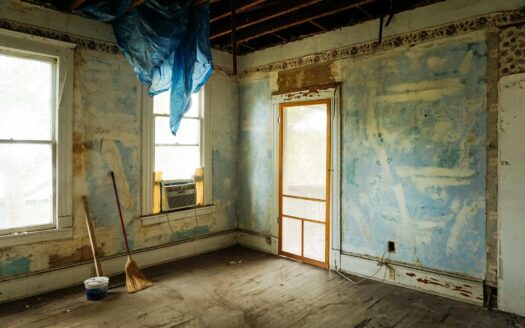 An empty room in an abandoned house with peeling walls and construction tools.