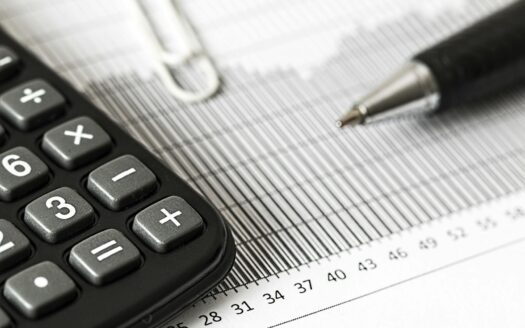 Close-up of a calculator and pen on a bar graph, representing finance and accounting.